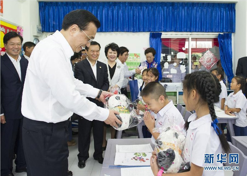 10月13日,正在泰国访问的国务院总理李克强参观具有110多年历史的清迈崇华新生华立学校。这是李克强向三年级学生赠送大熊猫玩具。新华社记者 黄敬文 摄
