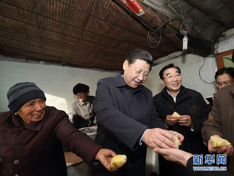 这是12月30日,习近平在龙泉关镇骆驼湾村困难群众唐荣斌家,与随行人员一起品尝蒸土豆。新华社记者 兰红光 摄